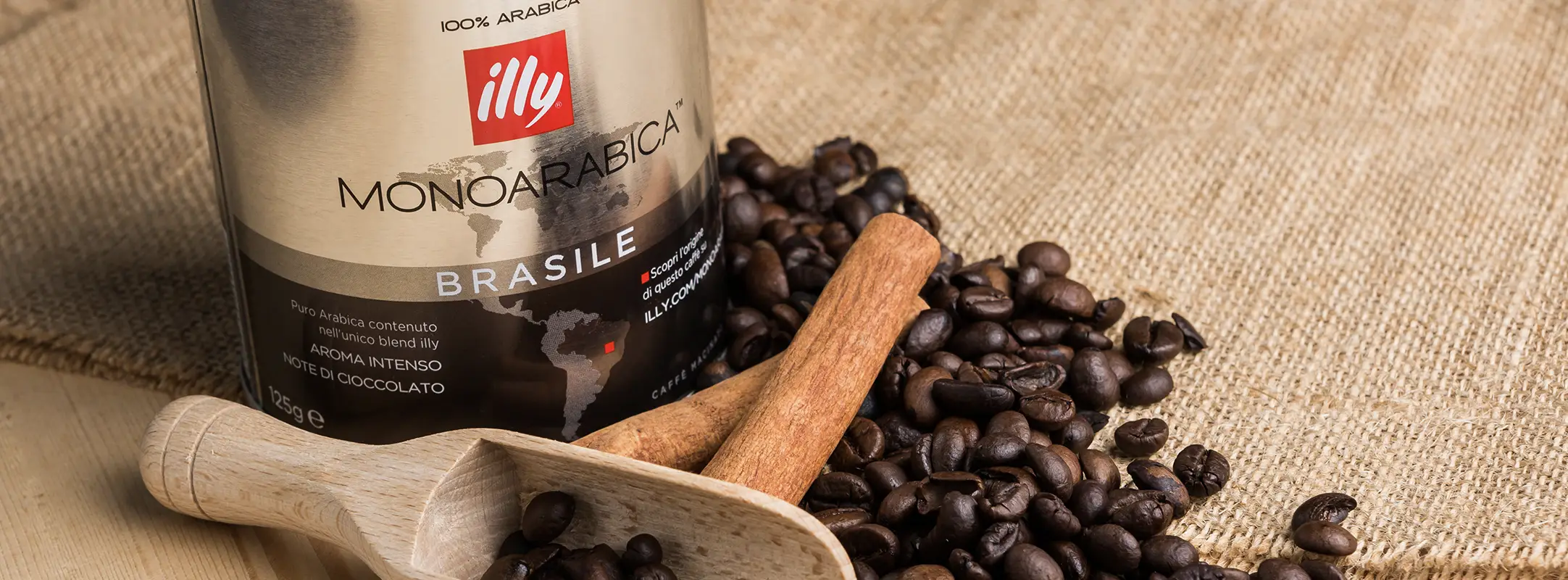 Illy koffie uit een blik met koffiebonen, kaneel en een lepel om koffiebonen mee te scheppen.