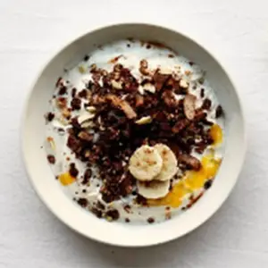 Bakje met kwark inclusief banaan, chocolade granola en iets wat op mango lijkt