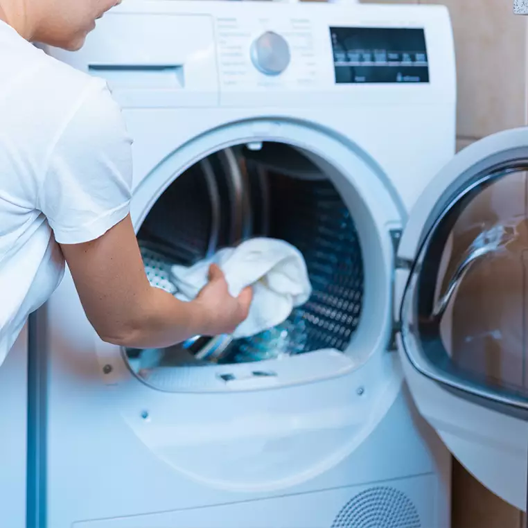 een jongen die de was uit de machine haalt met zijn wasmachine abonnement