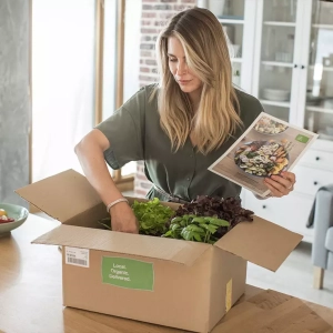 Een vrouw pakt haar hello fresh maaltijd abonnement uit