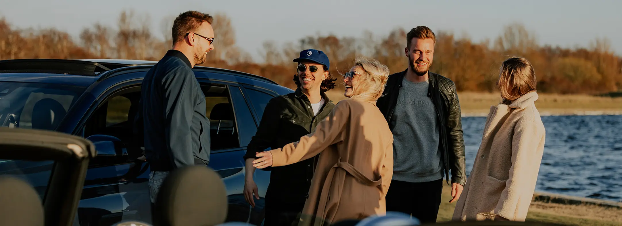 mensen komen bij elkaar rondom een auto bij een meertje