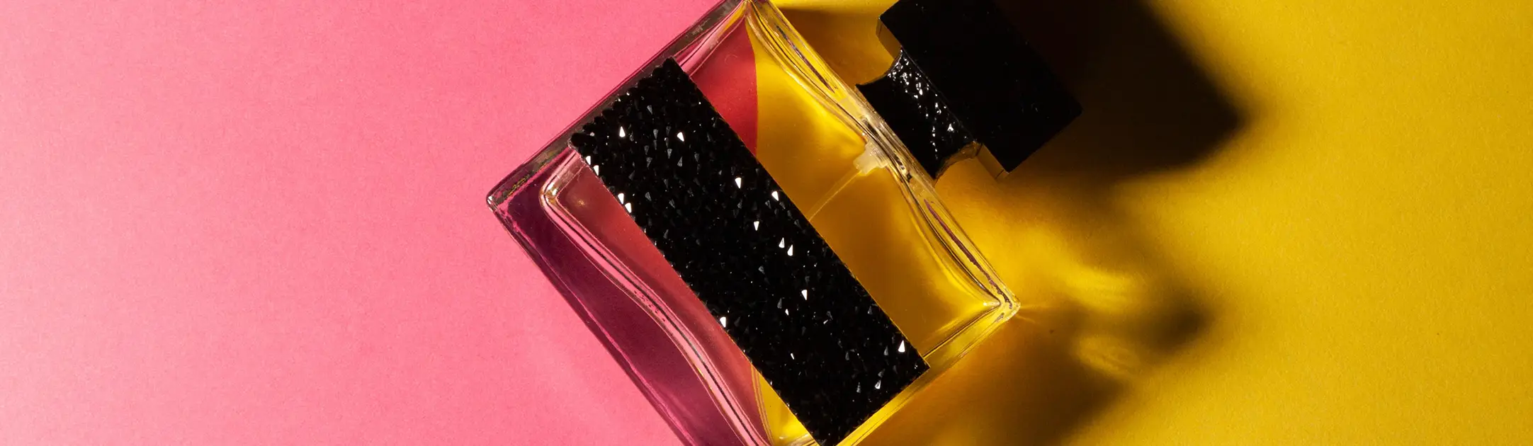 Flesje parfum met zwart etiket en dop op een gekleurde achtergrond