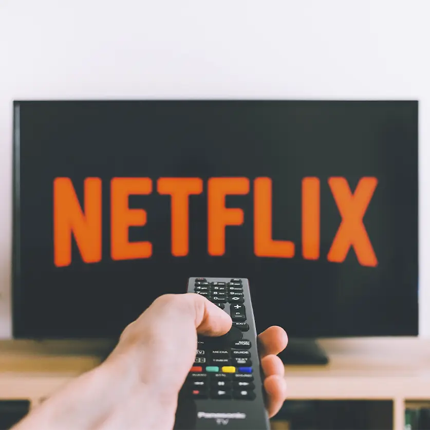 Persoon met afstandsbediening die richt op televisie met Netflix aan