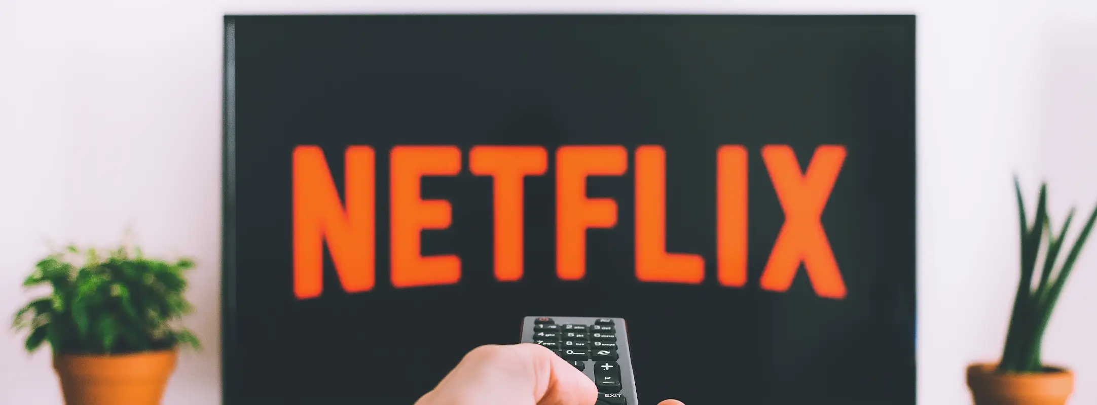Persoon met afstandsbediening die richt op televisie met Netflix aan