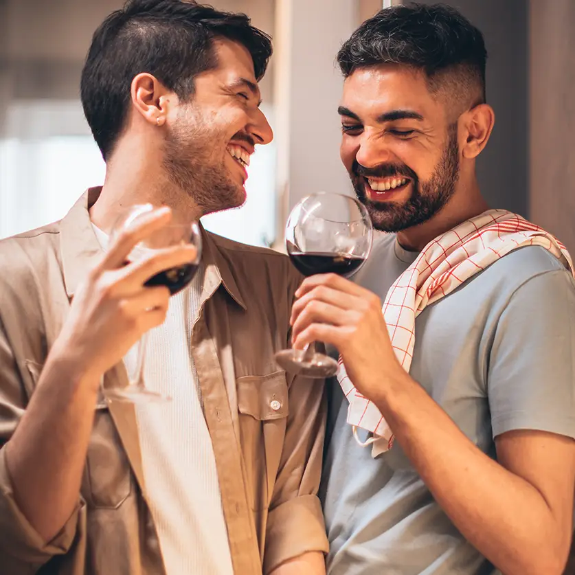 Twee mannen in de keuken met een glas rode wijn uit een wijnbox abonnement in hun hand