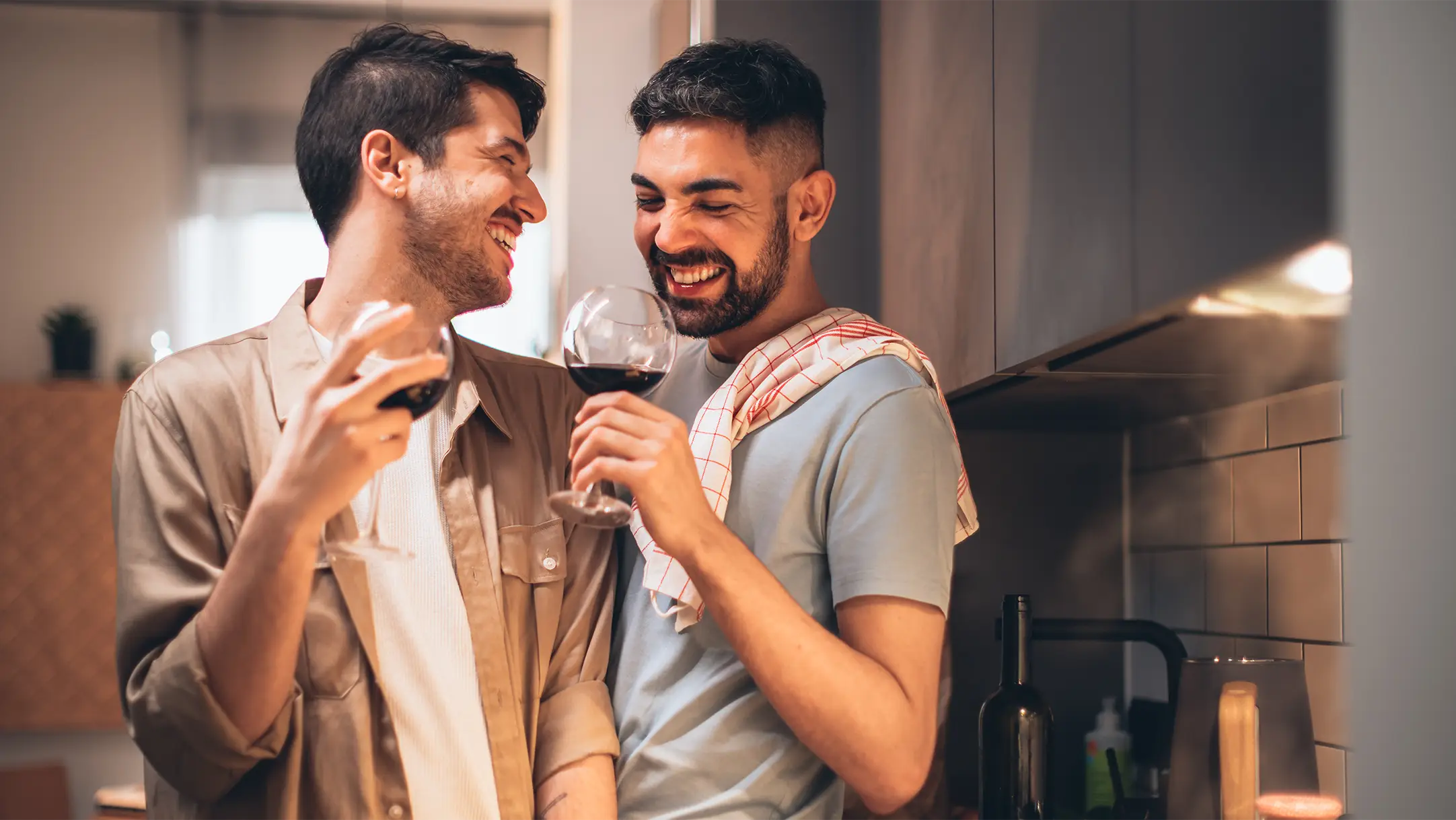 Twee mannen in de keuken met een glas rode wijn uit een wijnbox abonnement in hun hand