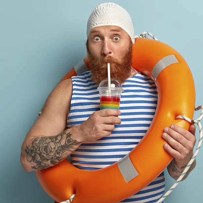 Man met badmuts, baard en reddingsboei in gestreept badpak