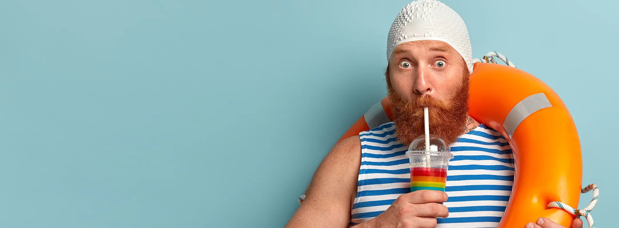 Man met witte badmuts, rode baard, milkshake en reddingsboei met oranje reddingsboei.