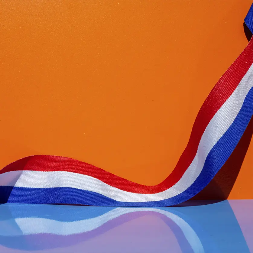 Oranje achtergrond met Nederlandse vlag op een tafel