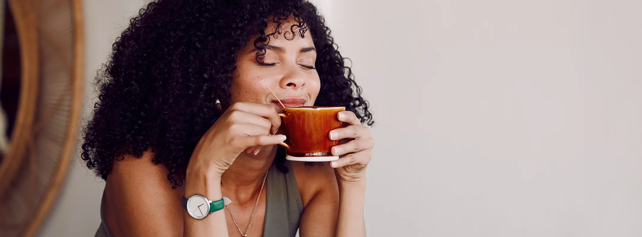 Vrouw die geniet van een vers gezet bakje koffie uit haar koffiemachine abonnement, zittend aan tafel.