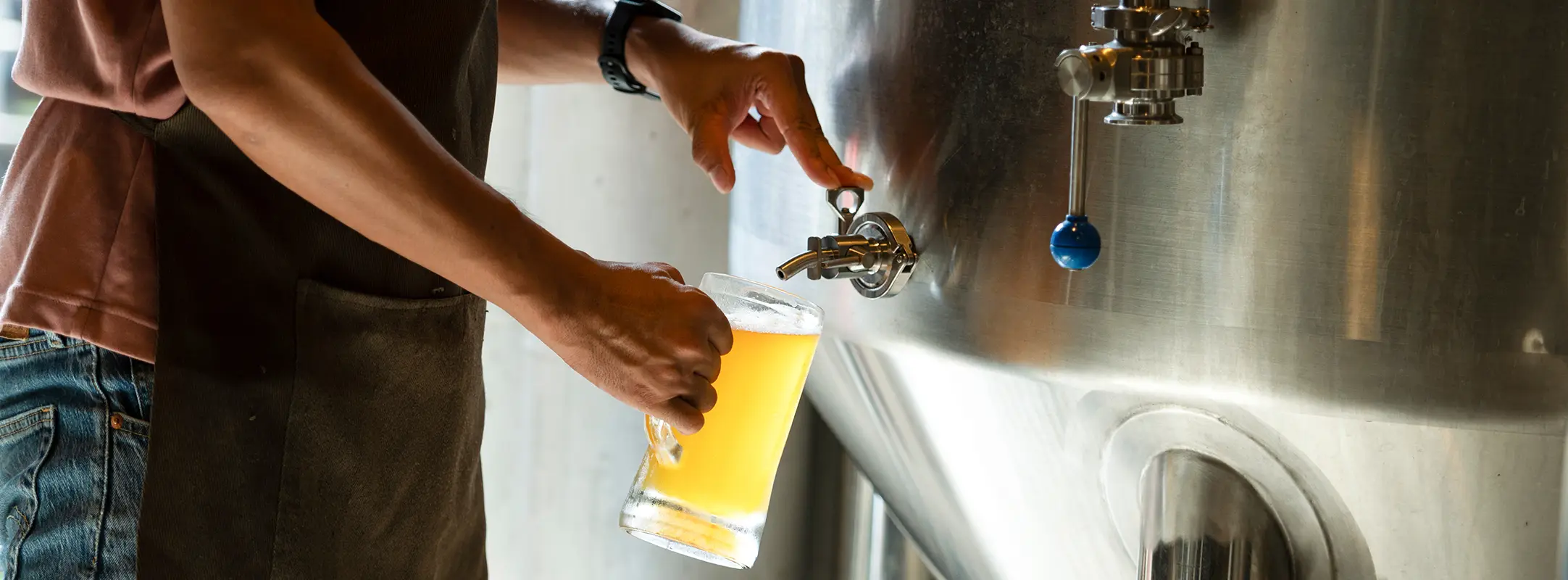 Brouwer van speciaalbier die zijn net gebrouwen bier proeft.