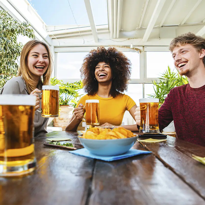 Vrienden die samen lachen en bier drinken uit een speciaalbier abonnement met chips