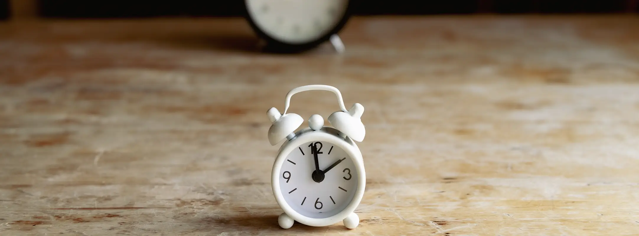 Wekker met daarachter nog een wekker op een tafel