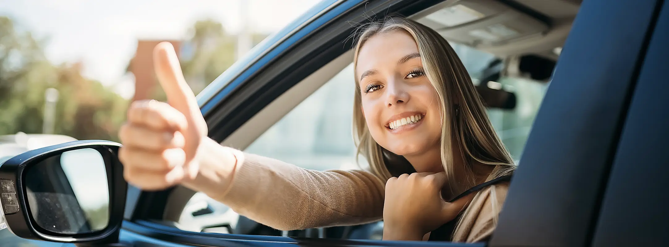 Vrolijke vrouw die in haar auto zit en haar duim uitsteekt omdat haar auto abonnement maandelijks opzegbaar is.